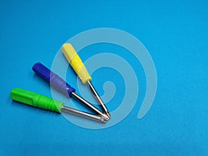 Three screwdrivers of different colors vertically on a blue background. copy space.