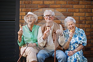 Three senior friends in the city, eating ice cream on a hot summer day. Summer vacation in the city. Pensioners on group
