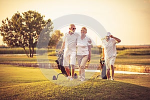 Three senior golfers. Focus is on man and woman