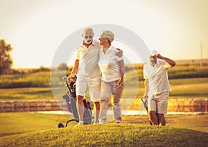 Three senior golfers. Focus is on man and woman