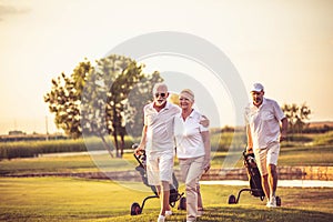 Three senior golfers. Focus is on man and woman