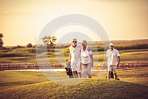 Three senior golfers. Focus is on man and woman.  Happy golfers