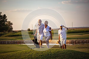 Three senior golfers. Focus is on man and woman.  Three senior golfers