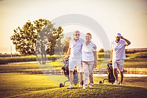 Three senior golfers walking and talking. It`s time for a friendly game