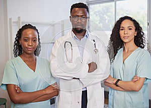 Three serious medical healthcare professionals stand in a row arms folded