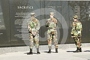 Three servicemen look at granite inscription on wall of Air Force Memorial, Arlington, Virginia in Washington D.C. area