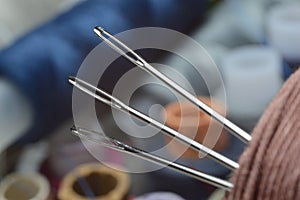 Three sewing needles are inserted into a spool of thread. close-up.