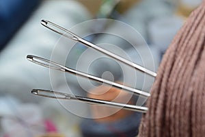 Three sewing needles are inserted into a spool of thread. close-up.
