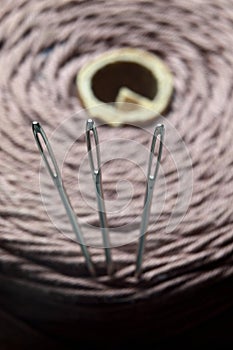 Three sewing needles are inserted into a spool of thread. close-up.