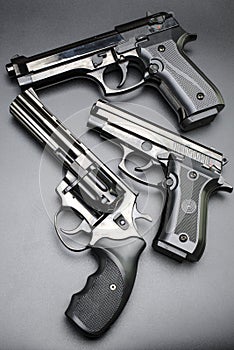 Three shiny black pistols on a black background