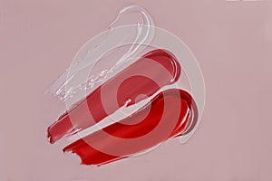 Three shiny lip gloss swatches on pink background