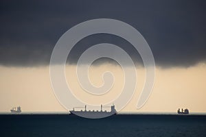 Three ships at sea in very cloudy weathe