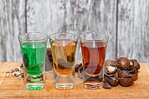 Three shots with different alcoholic beverages stand on a wooden stand