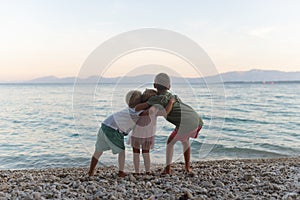 Three sibling hugging on the beach