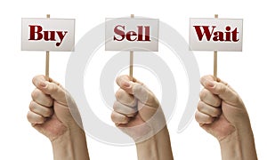 Three Signs In Fists Saying Buy, Sell and Wait