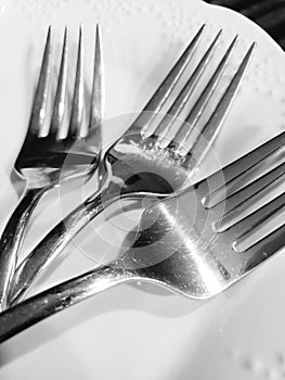 Three silver forks laying together on a white plate