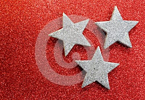 Three silver stars on bright red glittery illuminated background