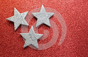 Three silver stars on bright red glittery texture