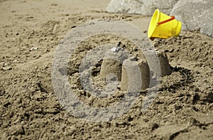 Three Simple Sandcastles with yellow bucket