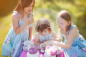 Three sisters playing tea party outdoors