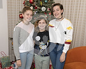 Three sisters standing in front of a Christmas tree