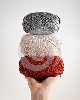 Three skeins of yarn in hand. Nice photo for a hobby, vertical orientation. Hobby aesthetics.