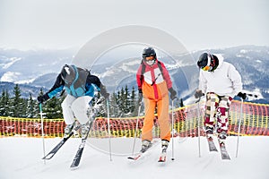 Three skiers skiing on fresh powder snow in mountains.