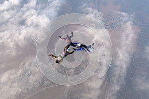 Formation skydiving. Three skydivers are in the sky.