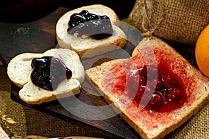 Three Slices of Baked Bread with Sweet Strawberry and Blueberry Jam on rustic wooden board