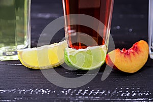 Three slices of different fruit and glasess with coctails on a b