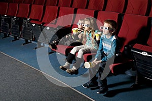 Three small children in 3D glasses watching a movie