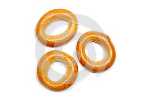 Three small dry bagels on a white background.
