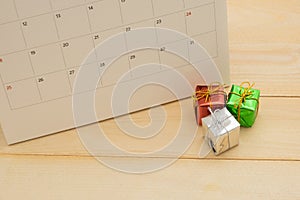 three small gift box putting front of calendar on wooden background