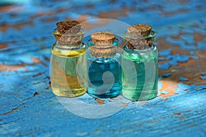 small glass bottles with colored oils stand on a worn blue table