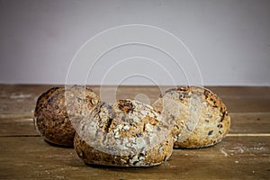 Three small loafs of French bread on display on a rustic wooden table, baguette style.