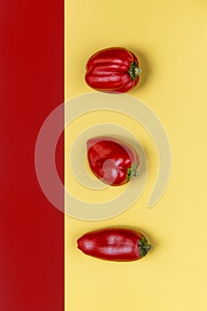 three small red peppers on a yellow background