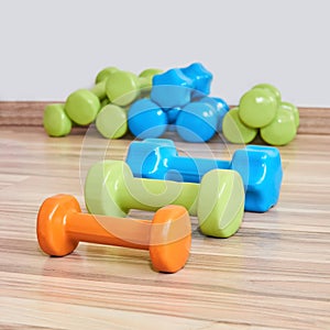 Three small rubberized dumbbells of different weights lie on the floor