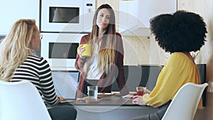 Three smart entrepreneur women talking while taking a break and having a breakfast in the kitchen at coworking place.