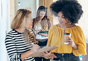 Three smart multiethnic businesswomen working while walking across the hall of coworking place