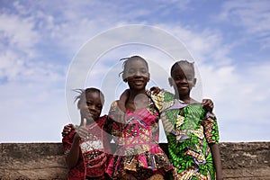 Three Smiling Africn Girls Posing Under A Beautiful Blue Sky On a Bridge