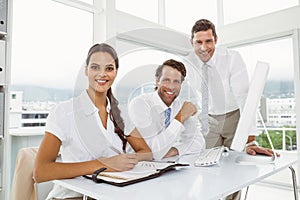 Three smiling business people at office desk