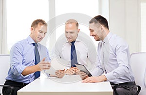 Three smiling businessmen with tablet pc in office