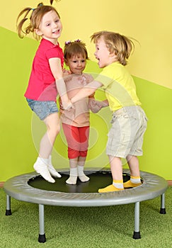 Three smiling children jumping on a