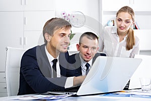 Three smiling coworkers working in company office