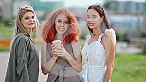 Three smiling diverse fashionable woman friend with waving hair posing outdoor looking at camera