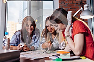 Three smiling female students learning together in classroom