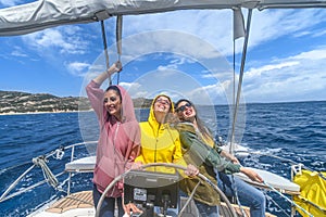 three smiling girls sailing with a boat in the ocean