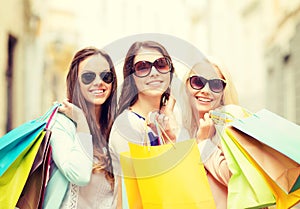 Three smiling girls with shopping bags in city