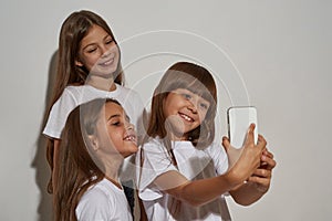 Three smiling girls taking selfie on smartphone