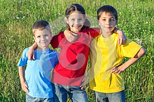 Three smiling kids on the meadow
